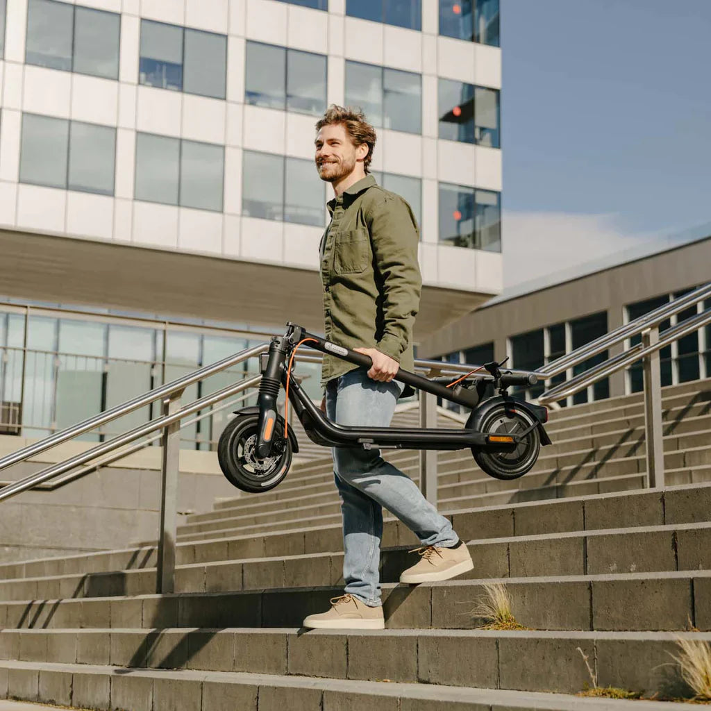 a man carrying a folded f2 segway ninebot