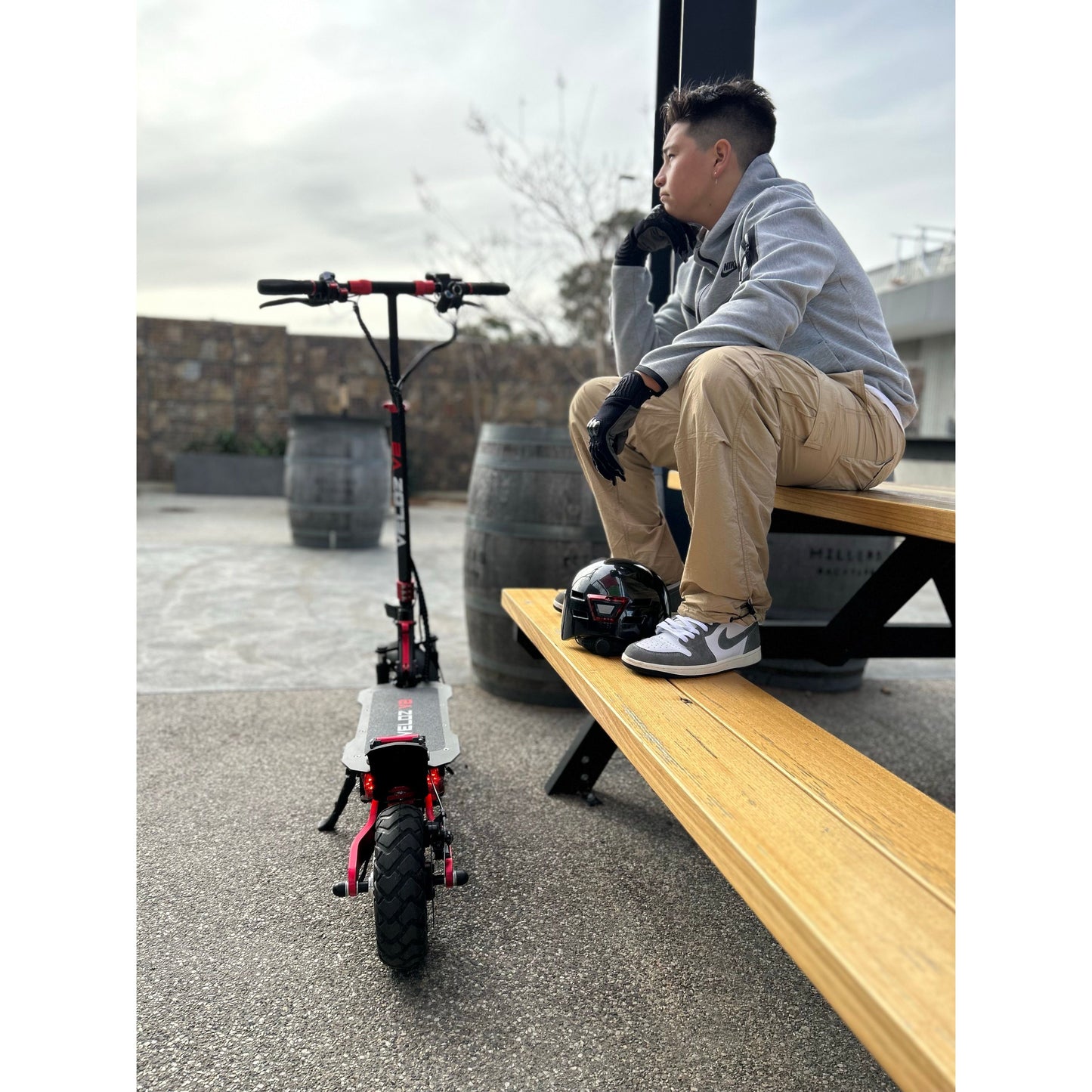 a teenager boy sitting next to his veloz v1 electric scooter