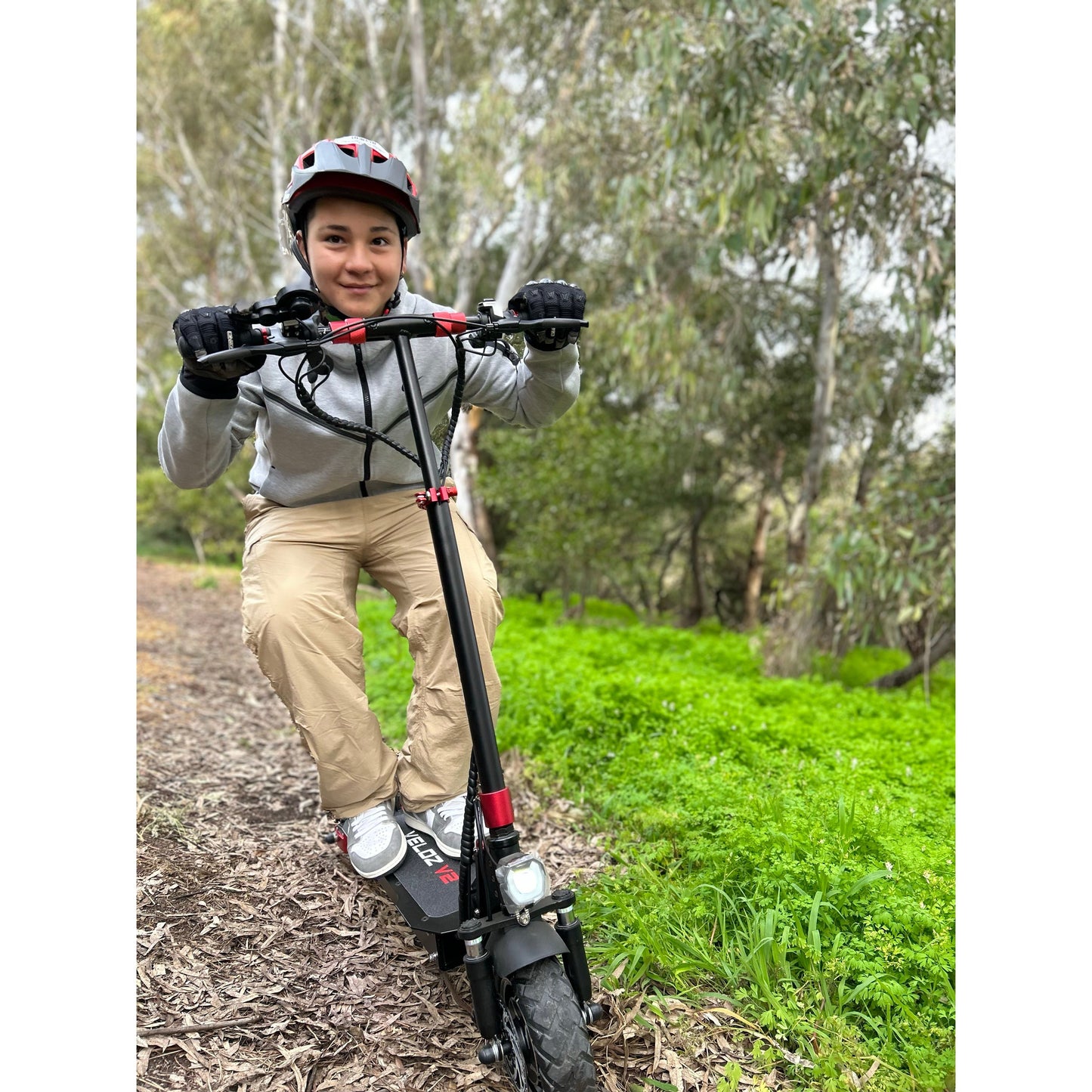 a happy teenager boy riding his veloz v1 electric scooter on grass